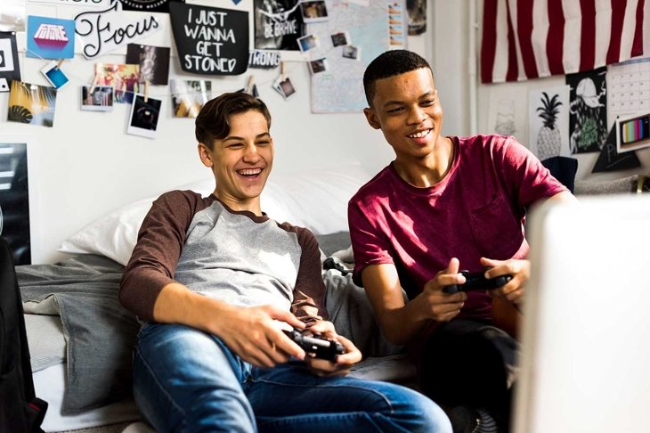 Teenage boys hanging out in a bedroom playing video games together