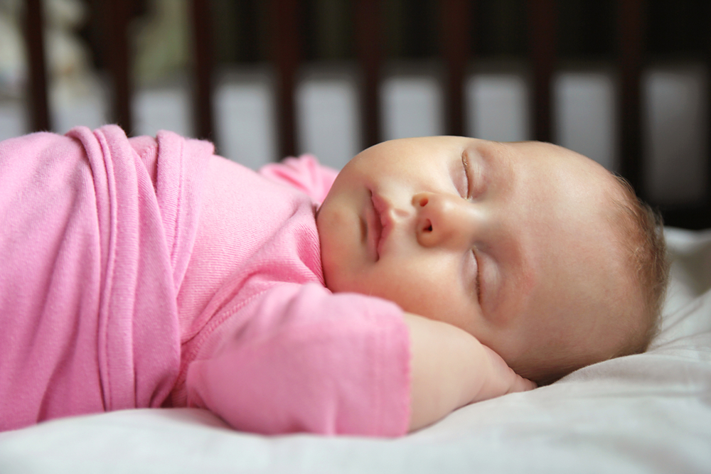 baby sleeping in pink swaddle