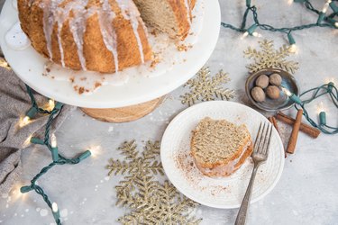 Cake stand with eggnog bundt cake and plate with a slice of cake and a fork