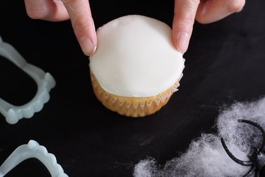 Pressing white fondant circle into frosting