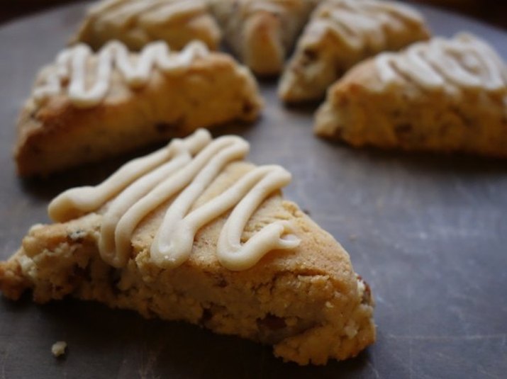 Maple pecan scones in a circle pattern against a dark countertop, with one scone in the foreground