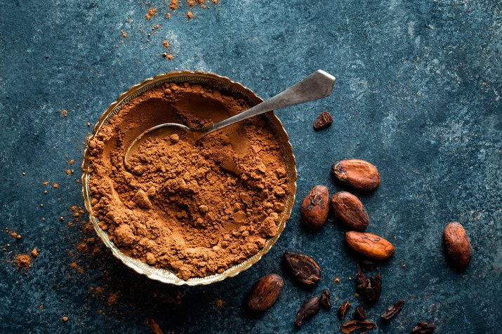 Cocoa powder and cacao beans on dark background, top view