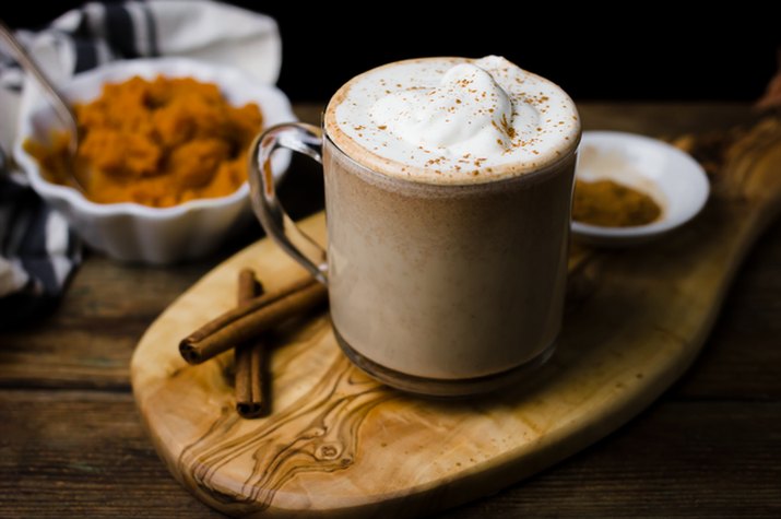 Pumpkin spiced latte in a glass mug on a wooden board