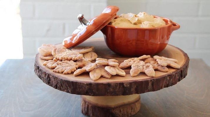 A pumpkin shaped container full of pumpkin butter and several cookies