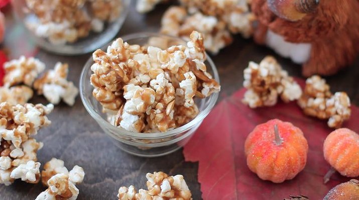 A bowl of pumpkin caramel corn surrounded by small pumpkins