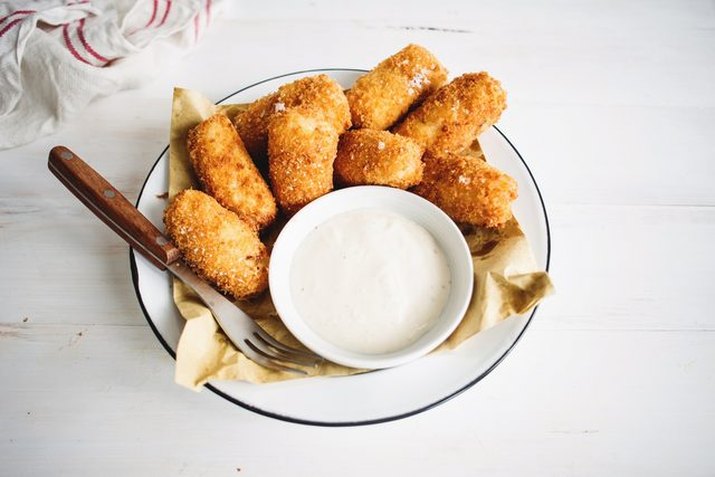 A plate of golden brown cheddar bacon tater tots with a side of ranch.