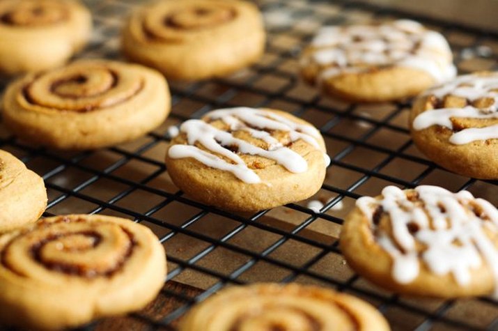 Freshly baked sweet potato cinnamon roll cookies sitting on a wire rack.